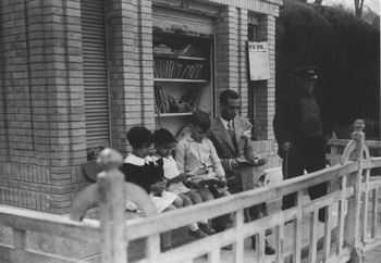 Adult i infants llegint al porxo d'una biblioteca